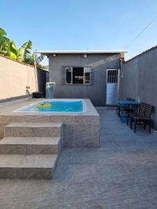 eine Terrasse mit einem Swimmingpool mit Tisch und Stühlen in der Unterkunft Beach house in Peruíbe in Peruíbe