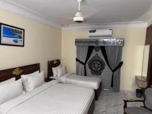 a hotel room with two beds and a window at Royal Continental DHA Karachi in Karachi