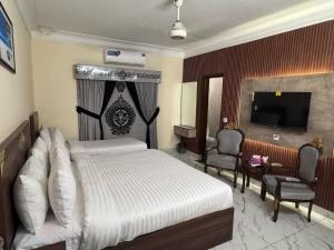 a bedroom with a bed and a television and chairs at Royal Continental DHA Karachi in Karachi +13 photos