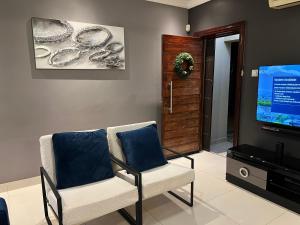 a living room with two chairs and a flat screen tv at Olive Exclusive in Gaborone