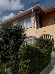 a yellow house with a balcony and bushes at Cleo luxe villa in Makandara