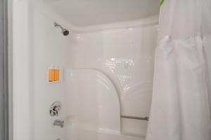 a shower with a white shower curtain in a bathroom at Whitefish Riverfront Hotel in Whitefish