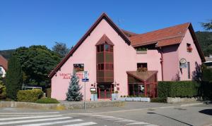 un grand bâtiment rose au coin d'une rue dans l'établissement Hotel Restaurant Aux Sapins, à Thann