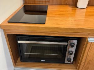 een magnetron die in een houten aanrechtblad is ingebouwd bij Apart's Sobremonte - Deptos Modernos in Rio Cuarto