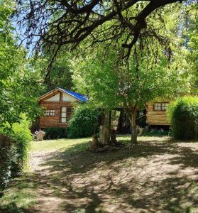 a log cabin with a tree in front of it at Mangoré Rústico Cabaña 1 in La Granja