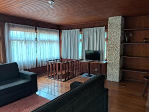 Chalés Vill'Agi في كامبوس دو جورداو: غرفة معيشة مع أريكة ومكتب وتلفزيون