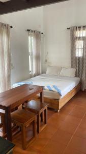 een slaapkamer met een bed en een houten tafel bij Homestay DGH in Alleppey +28 foto's