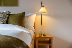 a bedroom with a bed with a lamp and a table at La Senda Smart Hotel Zuoz in Zuoz
