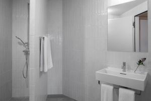 a white bathroom with a sink and a mirror at La Senda Smart Hotel Zuoz in Zuoz