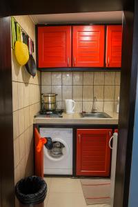 a small kitchen with red cabinets and a washing machine at Loïc Appart in Douala