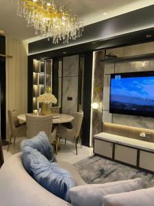 a dining room with a table and a large screen tv at Delft Apartemen in Gusung