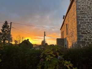 a sunset behind a brick building with a building at gîte La Maison d'Odette in Saint-Rémy-du-Plein