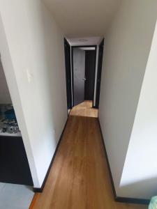 an empty hallway with white walls and wood floors at Alojamiento Cómodo y Hermoso en apartamento 7 personas Carnavales in Pasto