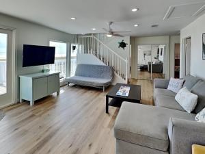 a living room with a couch and a tv at Our Infinity Pool in Galveston
