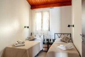 zwei Betten in einem Zimmer mit weißen Wänden in der Unterkunft Casuzze I Mori Museum Alloggi di Charme tra Mare Natura e Tradizione Siciliana in Marzamemi