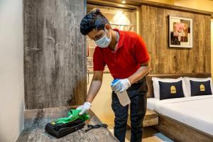 Super OAK Edassery's Sealine Villa Stay في كوتشي: رجل مقنع ينظف طاولة في غرفة