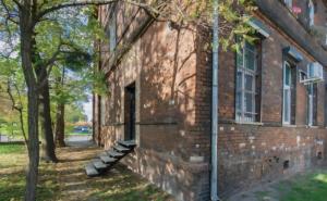 a brick building with a staircase next to a tree at Szampan i Truskawka in Toruń