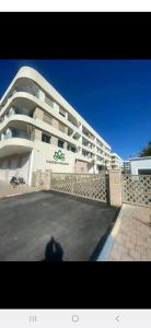 appartement résidence garden paradise plage bouznika في بوزنيقة: مبنى أبيض كبير يقف أمامه شخص