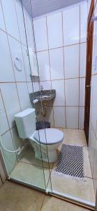 a bathroom with a toilet and a glass wall at Hospedaria Oliveira - Santo Amaro do Maranhão in Queimada