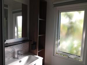 ein Badezimmer mit Waschbecken, Spiegel und Fenster in der Unterkunft Spacieux mobil home 40 m2 tt conf 5 p in Fréjus