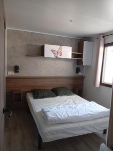 ein Schlafzimmer mit einem Bett mit einem Schmetterlingsschild an der Wand in der Unterkunft Spacieux mobil home 40 m2 tt conf 5 p in Fréjus