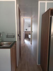 eine Küche mit einem Waschbecken und einem Flur in der Unterkunft Spacieux mobil home 40 m2 tt conf 5 p in Fréjus