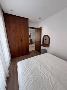 a bedroom with a white bed and wooden cabinets at bel et comfortable appartement centre agdal in Rabat