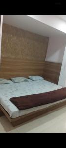 una cama con cabecero de madera y dos almohadas en Comic hotel, en Raipur