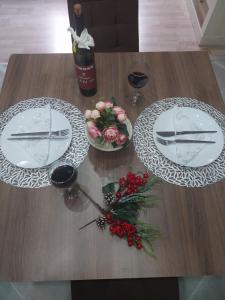 Park Apartment في كوكاني: طاولة خشبية مع طبقين ووعاء من الزهور