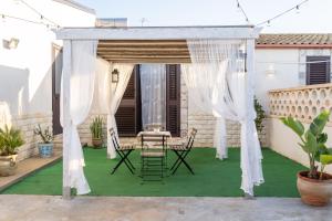 einen Pavillon mit einem Tisch und Stühlen auf einer Terrasse in der Unterkunft Casuzze I Mori Museum Alloggi di Charme tra Mare Natura e Tradizione Siciliana in Marzamemi