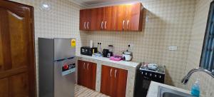 a kitchen with wooden cabinets and a stainless steel refrigerator at Purple Springs Elmina Suite #3 in Esamang