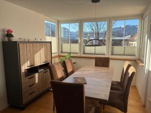 een eetkamer met een tafel, stoelen en ramen bij Alpen luaga Ferienwohnung in Sonthofen