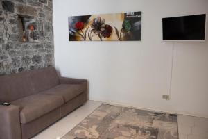 La Piccola Corte nel cuore di Como AC e wifi في كومو: غرفة معيشة مع أريكة ولوحة على الحائط