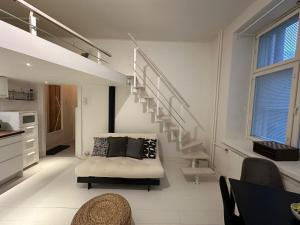 a living room with a staircase and a bed in it at Bright Loft Apartment Steps From Linnanmäki & Alppipuisto in Helsinki +9 photos
