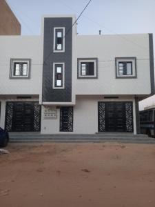 Femi في Keur Massar: مبنى أبيض بأبواب ونوافذ سوداء