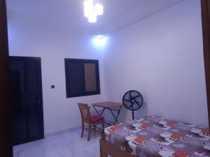 Femi في Keur Massar: غرفة نوم بها سرير وطاولة وكرسي