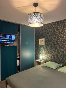 Un dormitorio con una cama y una lámpara de araña en Chez Olivier et Damien, en La Roche-sur-Yon