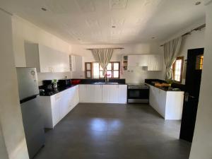 una grande cucina con armadietti bianchi ed elettrodomestici neri di Villa Soleil a Diani Beach
