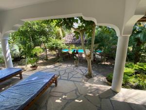 un patio con una panchina e un ombrellone di Villa Soleil a Diani Beach