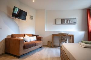 a living room with a couch and a tv on the wall at B&B Maison d'hôte et gite Mas d'Eymard in Arles