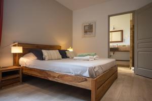a bedroom with a wooden bed with a mirror at B&B Maison d'hôte et gite Mas d'Eymard in Arles +37 photos