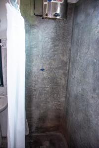 un bagno con doccia con parete in pietra di Tale Cabaña de campo a Huacalera