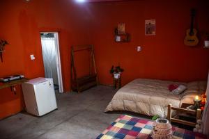 una camera da letto con pareti arancioni, un letto e un frigorifero di Tale Cabaña de campo a Huacalera