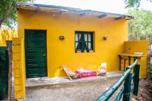 una casa gialla con due sedie e un tavolo di Tale Cabaña de campo a Huacalera Altre 4 foto
