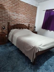een bed in een kamer met een bakstenen muur bij Casa Miramar in Miramar
