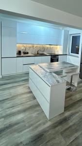 a kitchen with white cabinets and a marble counter top at Luxury Apartment private parking in Craiova
