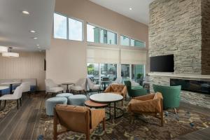 a lobby with tables and chairs and a fireplace at Residence Inn Pearland in Pearland