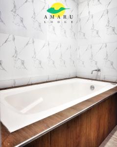 Una bañera en un baño con el cartel del hotel Aania en la pared. en Amaru Lodge, en Tingo María 10 fotos más