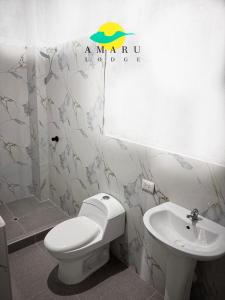 Un baño con un inodoro blanco y un lavabo. en Amaru Lodge, en Tingo María