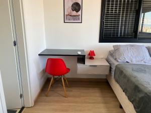 a bedroom with a desk and a red chair at Apt completo: ar cond piscina e academia no Centro in Taubaté +11 photos